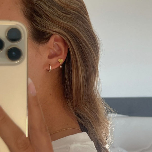Model iført Amora Hjerte Øreringe i 18K guldbelagt rustfrit stål.