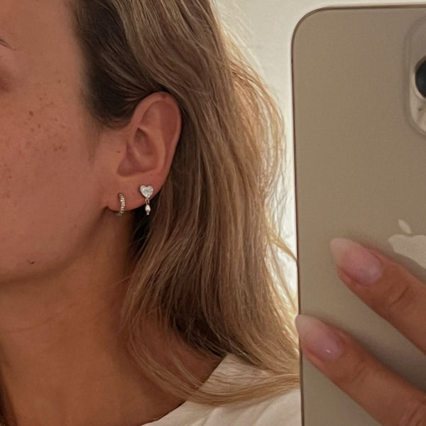 Model iført Amora Hjerte Øreringe i sølvfarvet rustfrit stål.