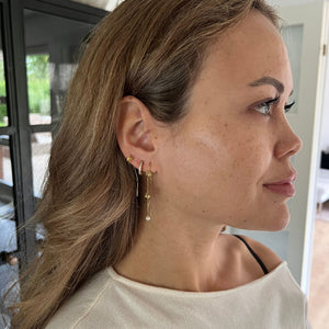 Sideprofil af Lilje Dangle Øreringe med elegant guldfinish.