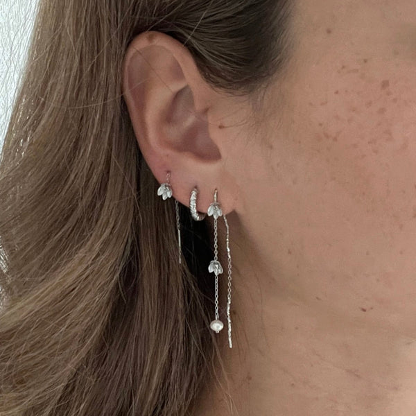 Model iført Lilje Øreringe i sølvfarvet rustfrit stål.