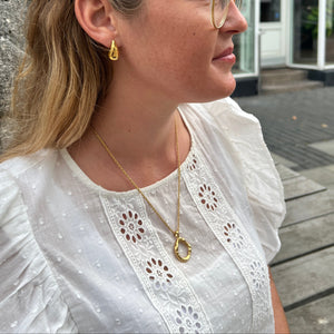 Model bærer Wavy Circle Halskæde i 18K guldbelagt rustfrit stål.
