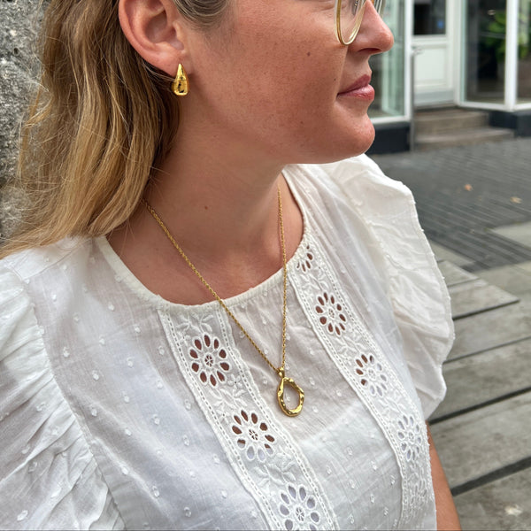 Model bærer Wavy Circle Halskæde i 18K guldbelagt rustfrit stål.